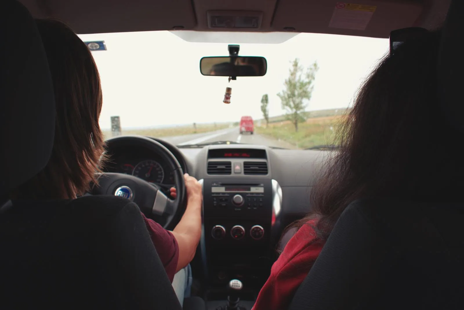 Vue intérieure depuis l'arrière d'une voiture circulant sur une route de campagne en plein jour