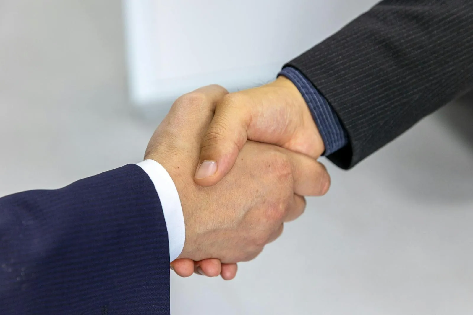Gros plan d'une poignée de main entre deux personnes en costume bleu marine et gris
