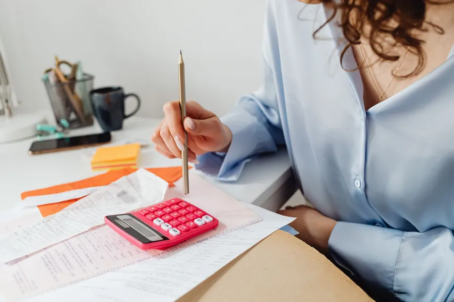 Femme calculant le décompte d'impayés d'assurance auto sur ses relevés bancaires avant régularisation