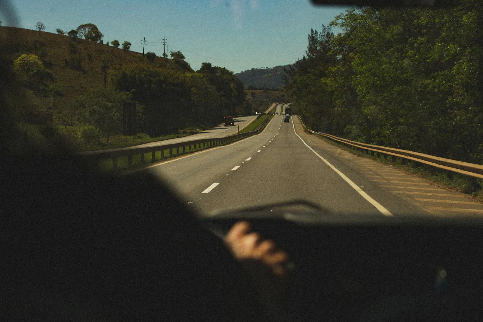 Vue à travers le pare-brise d'un véhicule circulant sur une route nationale en plein jour